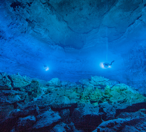 Divers in the illuminated submerged cave.